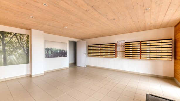 A spacious room with a wooden ceiling, tiled floor, and a wall-mounted storage unit.