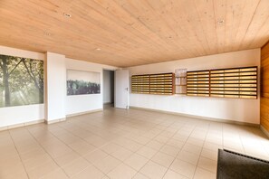 A spacious room with a wooden ceiling, tiled floor, and a wall-mounted storage unit. - Apartment 'Les Sapins 1' with Mountain View and Balcony (Les Adrets)