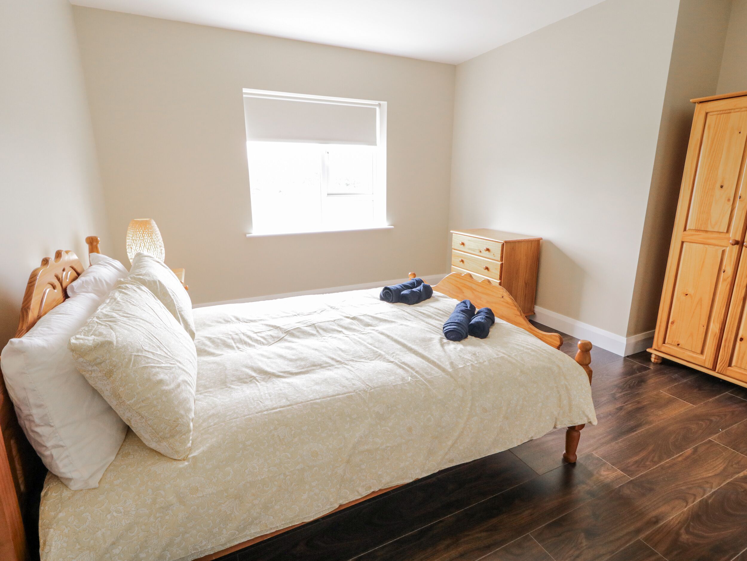 Una camera da letto con un letto, un comodino, una cassettiera e una finestra.