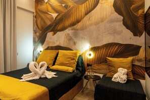 Hotellihuone, jossa on kaksi sänkyä, ja jokaisessa sängyssä on keltainen tyyny ja pyyhe.