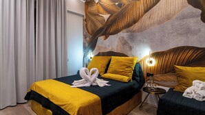 A hotel room with a bed, a side table, and a wall mural. - Luxury Procida in Naples station train (Napoli)