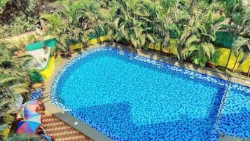 Una gran piscina al aire libre rodeada de exuberante vegetación y palmeras.