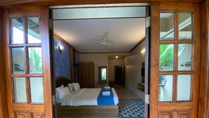 Een slaapkamer met een bed, een plafondventilator en uitzicht op de omgeving door een raam.