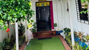 De ingang van Ashvem Beach Inn, met een receptie, een overdekte doorgang en potplanten.