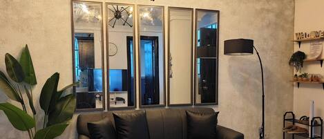 A living room with a sofa, coffee table, floor lamp, and a large mirror.