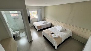 A hotel room with two beds, a bathroom, and a view of the street. - PENHA SOLAR INN (Centro Penha)
