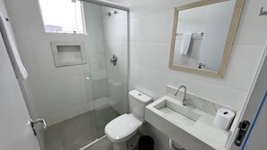 A modern bathroom with a glass shower enclosure, a toilet, a sink with a marble countertop, and a mirror with a wooden frame. - PENHA SOLAR INN (Centro Penha)