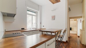 Una cocina moderna con encimera de madera, armarios blancos, una ventana y una puerta que da a otra habitación.