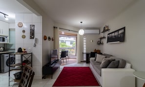 Een moderne woonkamer met een rode vloerkleed, een witte bank en een eethoek met een tafel en stoelen.