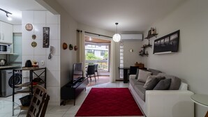 Una sala de estar moderna con un tapete rojo, un sofá blanco y un comedor con mesa y sillas.