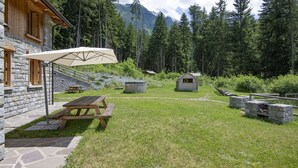 A rustic cabin with stone walls, a picnic table, and a covered umbrella.