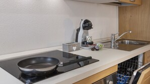 A kitchen with a black induction cooktop, a coffee maker, a toaster, and a sink.