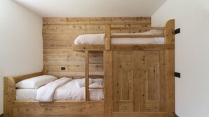 A bunk bed with a wooden headboard and a lower bed with pillows and a blanket.