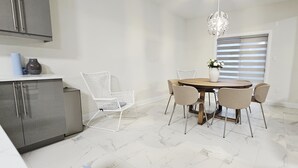 A dining area with a round table, four chairs, a vase with flowers, and a globe pendant light.