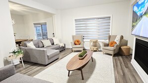 A modern living room with a grey sofa, a wooden coffee table, and a television mounted on the wall.