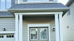 A two-story house with a front porch, a garage, and a well-maintained lawn.