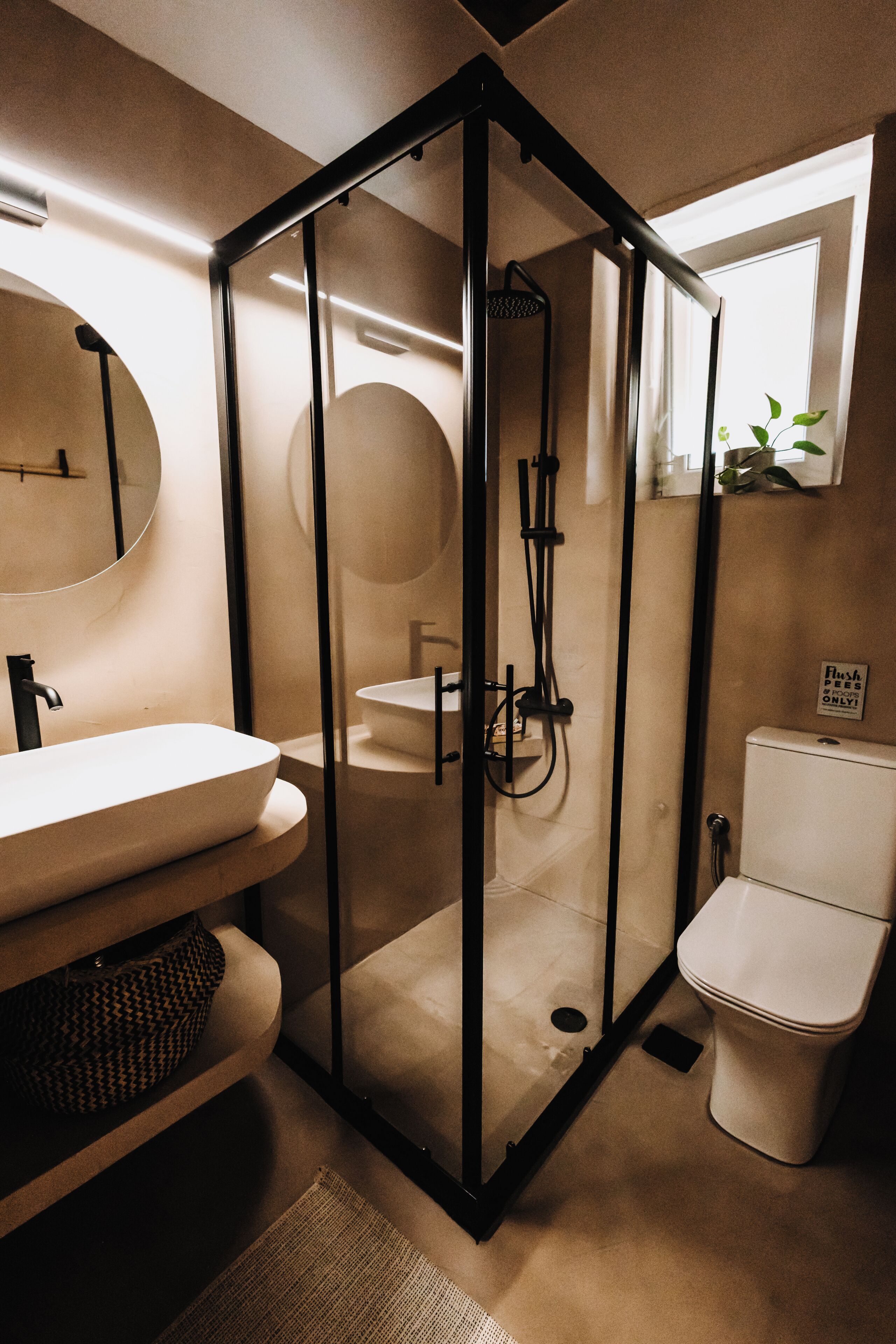 Un baño moderno con ducha de vidrio, un lavabo blanco y un inodoro.