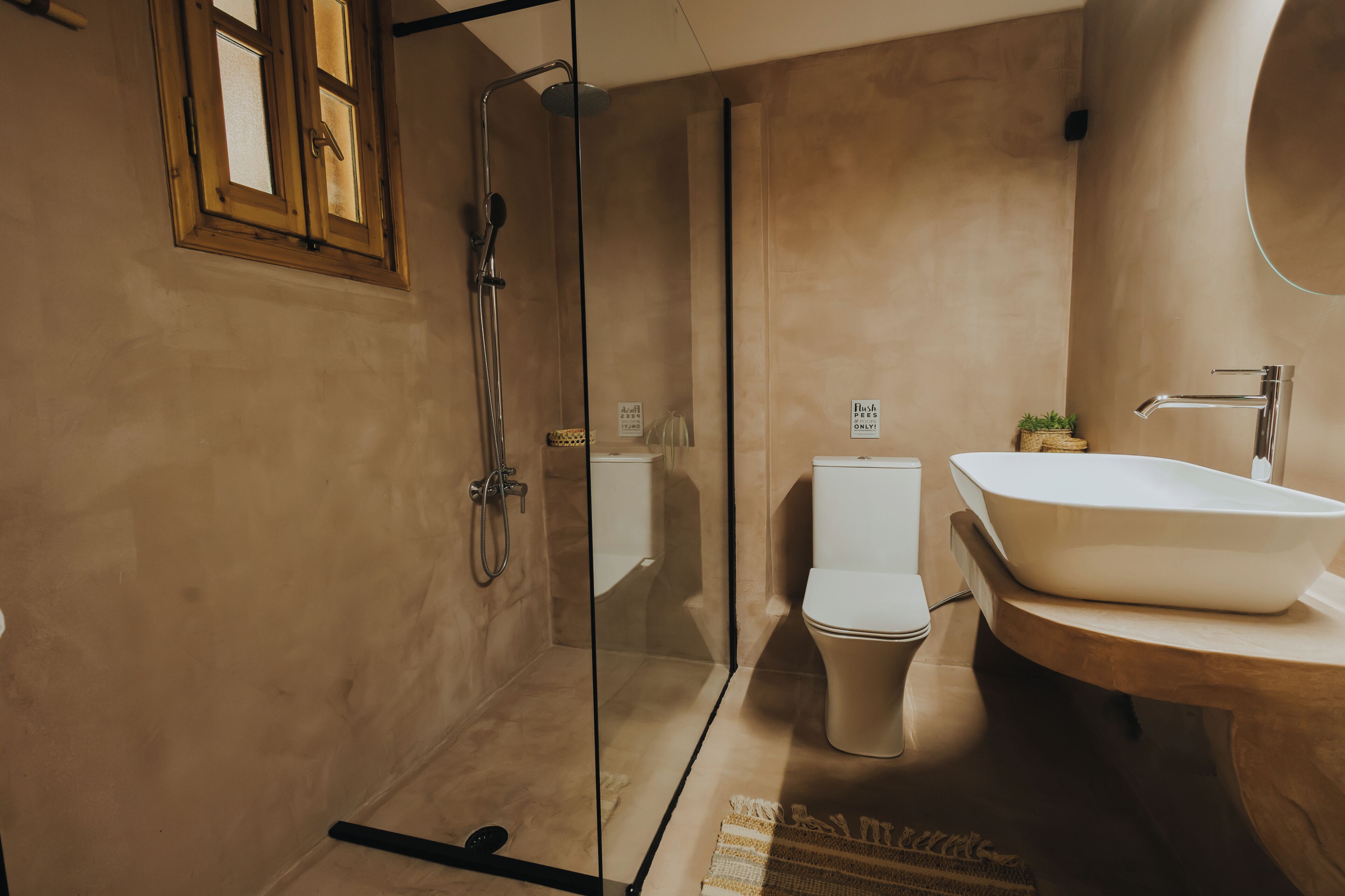 Een moderne badkamer met een douchecabine van glas, een wit toilet en een groot wastafelmeubel met spiegel.