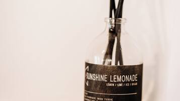 Uma garrafa de limonada Sunshine Lemonade com palitos pretos, identificada como não tóxica e produzida na Grécia, sobre uma superfície de madeira.
