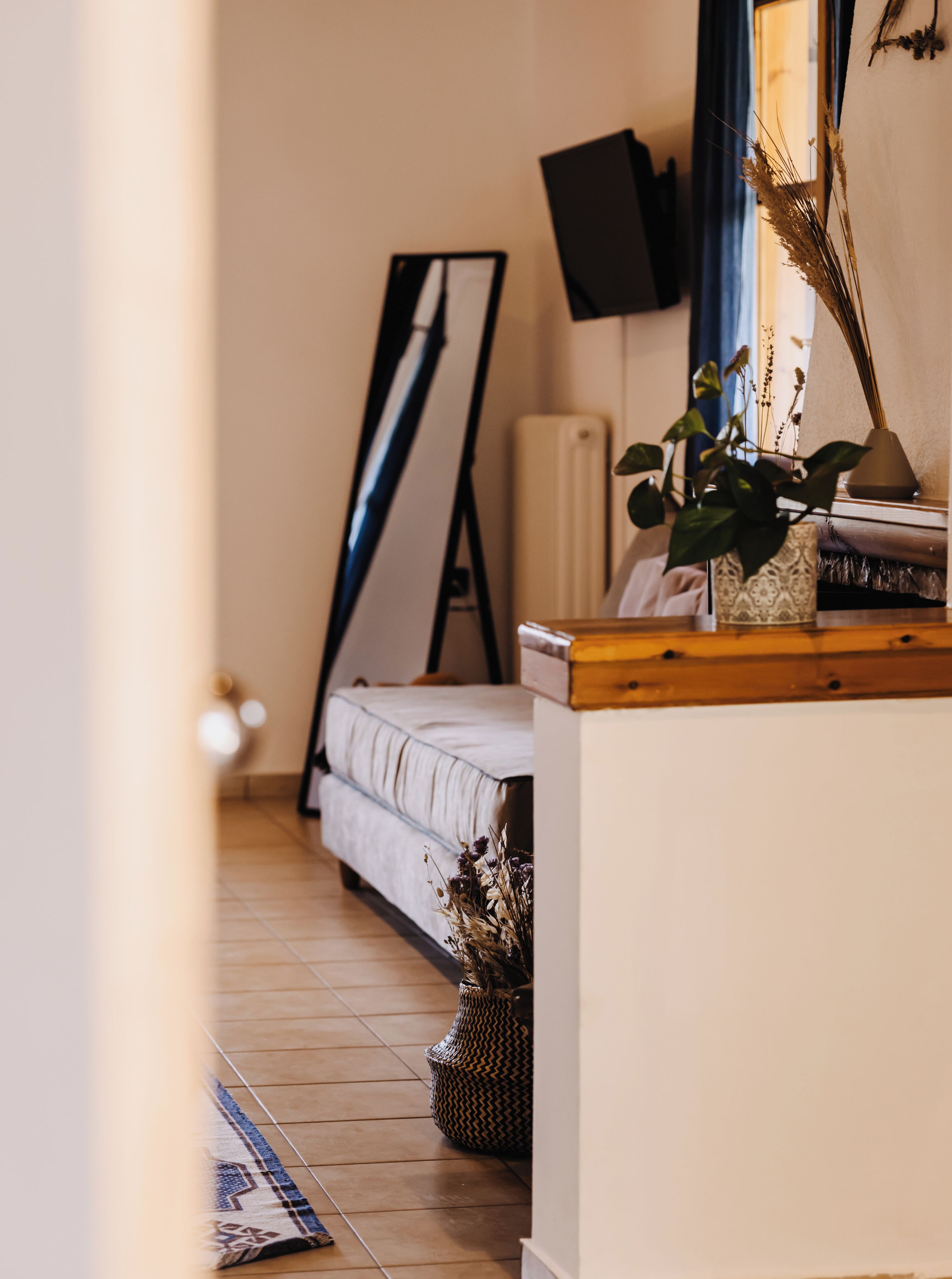 Een slaapkamer met een bed, een nachtkastje met een lamp, een tv aan de muur en een raam met gordijnen.