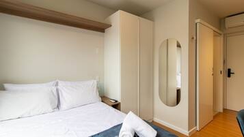 A hotel room with a bed, a nightstand, a mirror, and a wardrobe.
