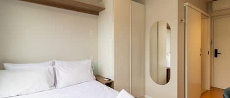 A hotel room with a bed, a nightstand, a mirror, and a wardrobe.