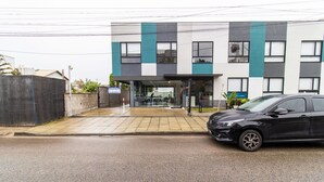 A modern building with a gated entrance, a car parked in front, and a visible signboard. - Modern Studio Just Minutes From the Beach Sid0209 (Florianópolis)
