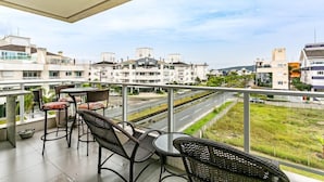 A balcony with wicker furniture and a view of a road and buildings.