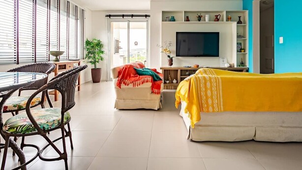A living room with a sofa, a TV, and a dining area with chairs and a table.