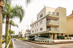 A modern multi-story building with balconies, a central staircase, and a parking area. - Apto 2Q e churrasq. 800m da praia de Jurerê SGA202 (Florianópolis)