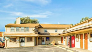 A motel with a parking lot, a red Coca-Cola refrigerator, and a sign with the number 700.
