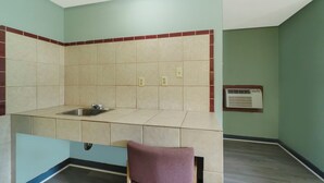 A small kitchen with a sink, a window air conditioner, and a chair. - Capital O Parker Motel Clute Jackson Tx 332 (Clute)
