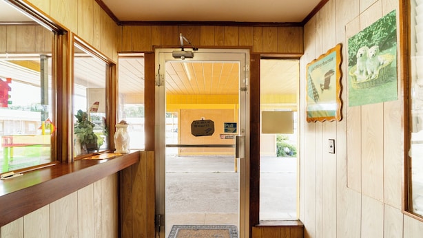 A wooden interior hallway with a door leading to a bright room. - Capital O Parker Motel Clute Jackson Tx 332 (Clute)