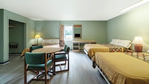 A hotel room with two single beds, a dining table with chairs, a small desk, and a window with curtains. - Capital O Parker Motel Clute Jackson Tx 332 (Clute)