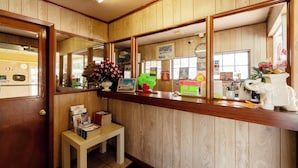 A reception area with wooden paneling, a reception desk, a small table with brochures, and a clock on the wall. - Capital O Parker Motel Clute Jackson Tx 332 (Clute)