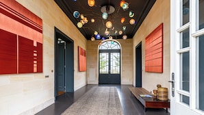 A hallway with a patterned carpet, a bench, and a decorative ceiling light fixture.
