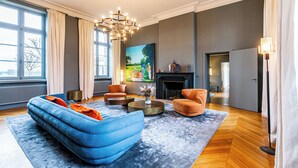 A modern living room with a blue sofa, orange armchair, and a fireplace.