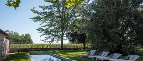 A swimming pool with lounge chairs and a grassy area.