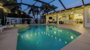 Indendørs swimmingpool med glastag, omgivet af liggestole og et spiseområde.