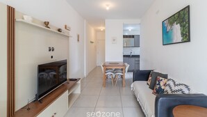 Una sala moderna con televisor, mesa de comedor y sofá.