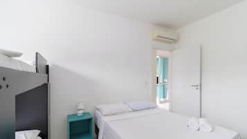 A bedroom with a bunk bed, a single bed, a nightstand with a lamp, and a door leading to a balcony.