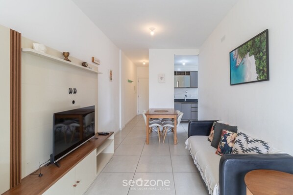 A modern living room with a TV, dining table, and sofa.
