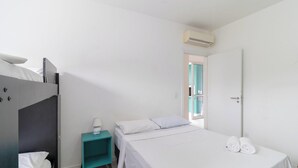 Un dormitorio con cama, mesita de noche, armario y puerta que da a otra habitación.