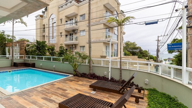 Edificio residencial con piscina, zona de estar exterior y vistas al mar.