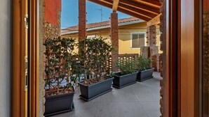 Zona exterior coberta amb columnes de maó, plantes en testos i un cel clar.