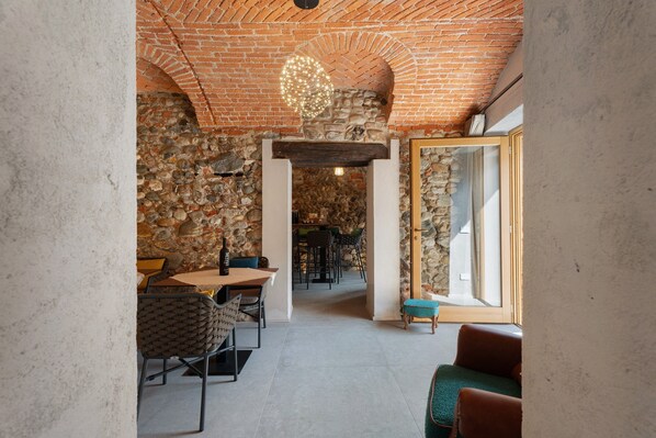 A dining area with a brick wall, stone archway, and a view through a glass door.