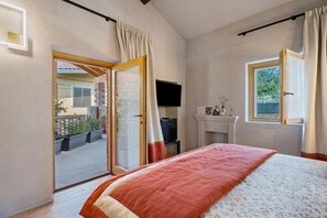 A bedroom with a bed, a television, a fireplace, and a balcony.