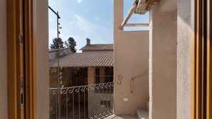 A balcony with a metal railing, a tiled roof visible through the railing, and a beige wall. - Room 'Baloss' with Mountain View, Wi-Fi, and Air Conditioning (Borgomanero)