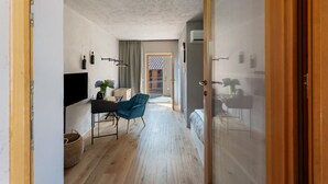A modern interior with a wooden floor, a desk with a chair, a bed, and a sliding glass door. - Room 'Baloss' with Mountain View, Wi-Fi, and Air Conditioning (Borgomanero)