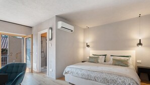 A bedroom with a bed, a chair, a shower, and an air conditioning unit. - Room 'Baloss' with Mountain View, Wi-Fi, and Air Conditioning (Borgomanero)